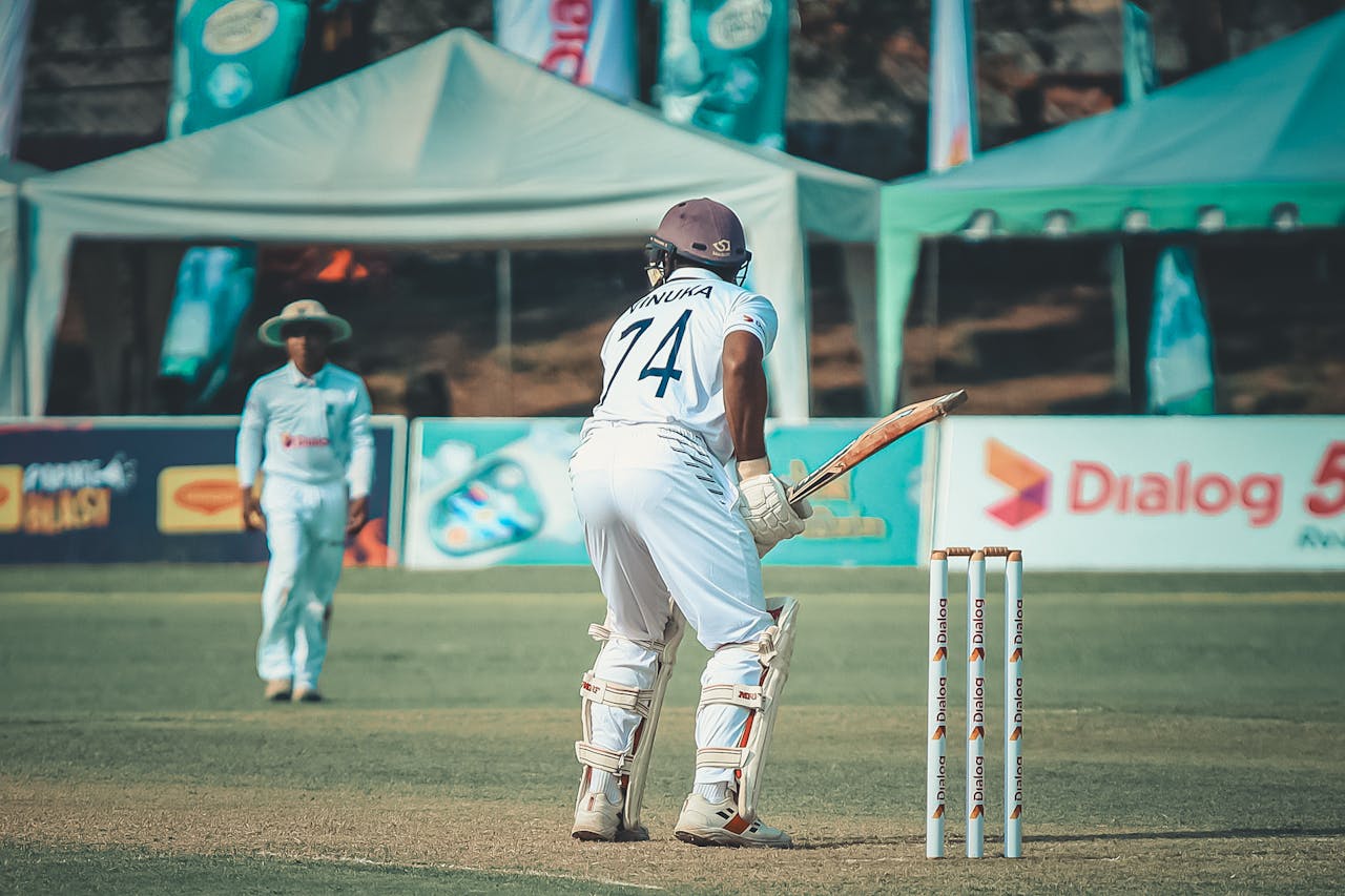 Cricketer in uniform ready to bat on a sunny day. Outdoor sports scene.